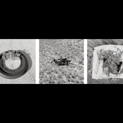 Three black-and-white photographs: dense boot-print patterns in sand, a wooden power pole densely rigged with crossarms and high-voltage wires, and the rusted, bullet-riddled body of an abandoned car in open desert.