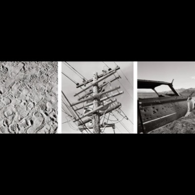 Three black-and-white photographs: a single cloud floating over dark desert dunes, two crossed sticks laid on cracked sandstone, and a large, rounded boulder wedged between two rock walls.