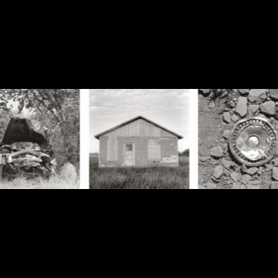 Three black-and-white photographs: a wrecked car’s crumpled hood beneath a tree, a weathered wood-sided barn under a gabled roof in an open field, and a chrome hubcap lying face-up amid loose rocks.